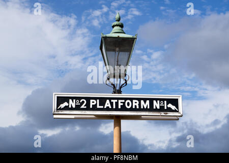 Signe de la plate-forme à l'ancienne avec l'entraîneur d'un voyant à l'héritage de la ligne de chemin de fer. Prises d'angle bas à haut dans ciel bleu et nuages fascinants. Banque D'Images