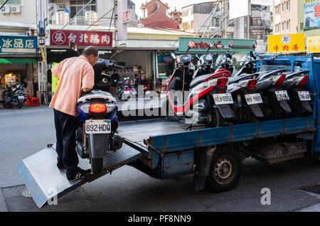 20 février 2018, Tainan, Taiwan : streetview de l'homme mettant un scooter dans un un camion plein de scooters en Tainan Taiwan Banque D'Images