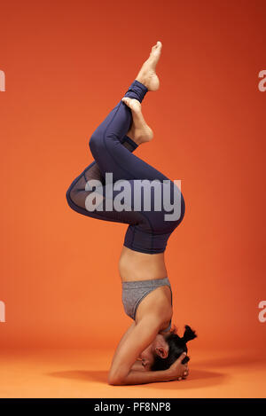 Yoga asanas eagle élégant woman show sur fond de couleur orange studio Banque D'Images