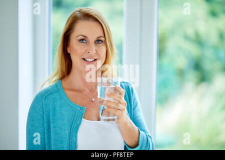 S Femme tenant un verre d'eau Banque D'Images