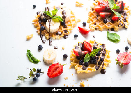 Gaufres avec les baies fraîches - fraise, myrtille, banane et chocolat topping. Dessert sucré sur fond blanc. Banque D'Images