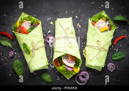 La nourriture à la mode. Tortilla épinards vert avec le poulet et les légumes . Vue de dessus sur noir. Collation santé. Banque D'Images
