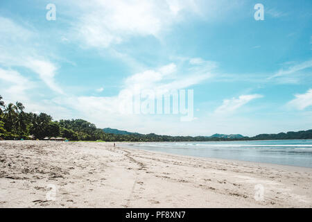 Plage de sable propre de Sámara, province de Guanacaste au Costa Rica par une chaude journée d'été avec un ciel bleu et quelques touristes Banque D'Images