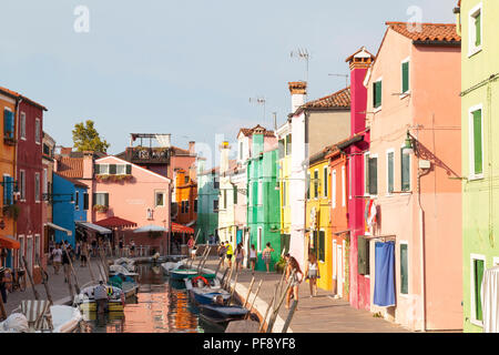 Coucher du soleil dans le pittoresque village de pêcheurs sur l'île de Burano, Venise, Vénétie, Italie. Canal avec des bateaux, des réflexions, des touristes Banque D'Images