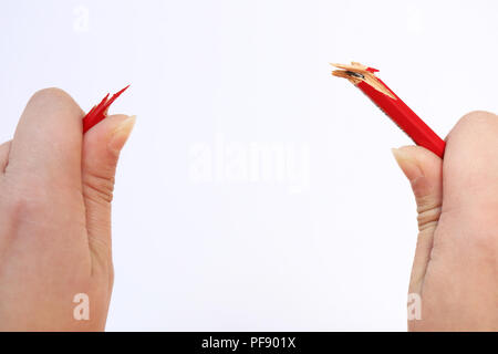 Deux mains tenant un crayon rouge qui vient cassé sous la pression. Notion de stress, de la colère, la pression sur le lieu de travail, un rôle parental Banque D'Images
