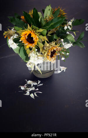 À la légère baisse par rapport à un vase de mourir, d'arrangement de fleur grand une fois mourir maintenant lumineux soleil fleurs dans un vase sur une très grande table à manger en marbre Banque D'Images