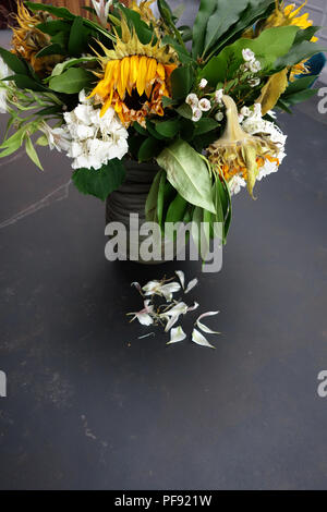 À la légère baisse par rapport à un vase de mourir, d'arrangement de fleur grand une fois mourir maintenant lumineux soleil fleurs dans un vase sur une très grande table à manger en marbre Banque D'Images