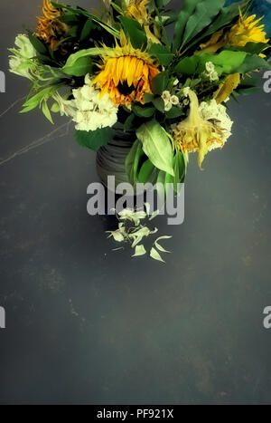 À la légère baisse par rapport à un vase de mourir, d'arrangement de fleur grand une fois mourir maintenant lumineux soleil fleurs dans un vase sur une très grande table à manger en marbre Banque D'Images