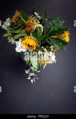 À la légère baisse par rapport à un vase de mourir, d'arrangement de fleur grand une fois mourir maintenant lumineux soleil fleurs dans un vase sur une très grande table à manger en marbre Banque D'Images