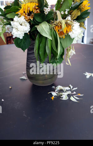 À la légère baisse par rapport à un vase de mourir, d'arrangement de fleur grand une fois mourir maintenant lumineux soleil fleurs dans un vase sur une très grande table à manger en marbre Banque D'Images