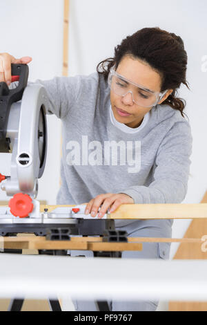 Femme attrayante à l'aide d'circualr carpenter vu dans un atelier Banque D'Images