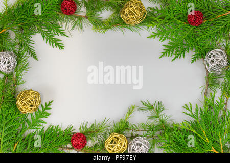 Une bordure de cèdre, de pin blanc et de mélèze laricin, avec des branches de rameaux d'or et d'argent et ornements boules rouge avec copie espace au milieu de votre message Banque D'Images