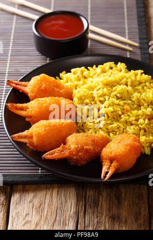 Fast food chinois pinces de crabe surimi dans la chapelure avec du riz jaune close-up sur une plaque sur une table verticale. Banque D'Images