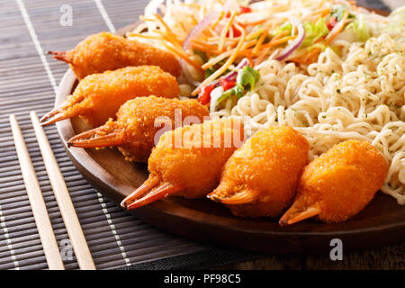 Pinces de crabe servi avec nouilles Udon pané et salade de légumes frais sur une assiette sur la table horizontale. Banque D'Images