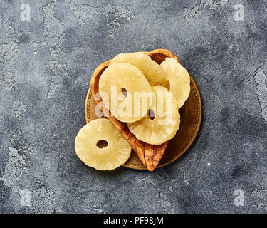 Ananas séché bagues sur un tableau gris. Haut viw de paneapple doux tranches. Banque D'Images