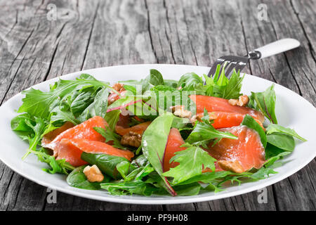 Poisson rouge salade saine feuilles de laitue sur une assiette blanche sur une vieille table rustique, recette facile, vue du dessus Banque D'Images