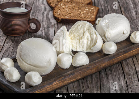 Boules de mozzarella sur une sombre et coupe d'argile avec du lait sur une vieille table rustique, vue du dessus Banque D'Images