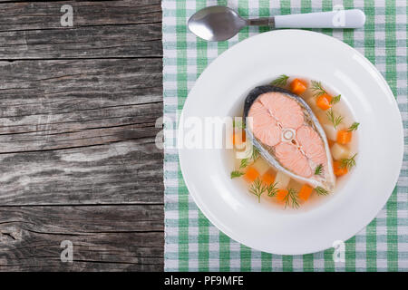 Soupe au saumon avec des légumes et de l'aneth dans un plat large rebord blanc sur une nappe sur une vieille table rustique,Vue de dessus Banque D'Images