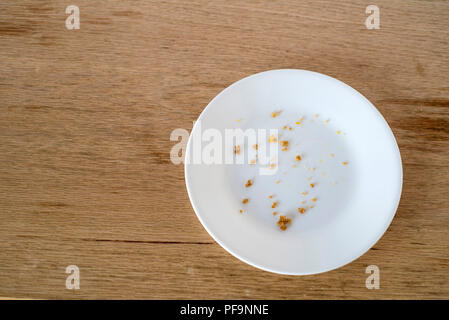 Plaque blanche avec des miettes de nourriture seulement assis sur une table en bois - tous terminé Banque D'Images