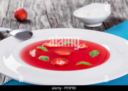 Soupe de fraises glacée avec des morceaux de fraises et des feuilles de menthe dans un plat traditionnel de Noël finlandais, soupe, projecteurs, close-up Banque D'Images