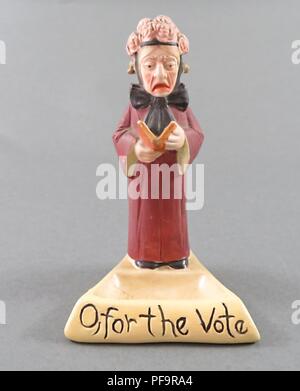 Figurine en céramique représentant une femme plus âgée, debout, portant un chapeau rose orné et un long manteau rouge, et la lecture d'un livre, avec une légende à la base de la figurine qui lit 'O, pour le vote,' produit par l'entreprise allemande de Schafer et Vater tant pour les marchés britannique et américain, 1900. () Banque D'Images