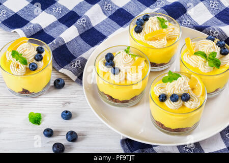 Petit-déjeuner sain en couches - dessert aux bleuets et au citron dans le verre tasses décorées de crème fouettée, de tranches de citron et menthe et serviette de cuisine, vue depuis l'ab Banque D'Images