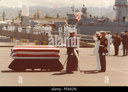 Photographie couleur, montrant plusieurs unités de militaires, y compris les United States Marine Corps (USMC) membres, au garde-à-vous et saluer un cercueil recouvert du drapeau américain, reposant sur un quai, avec l'USS Brewton (FF-1086) visible à l'arrière-plan, photographié lors de la guerre du Vietnam, 1970. () Banque D'Images