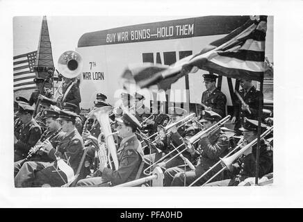 Photographie noir et blanc, montrant une armée, brass band, les musiciens portant des vêtements militaires (avec des ailes sur leurs manches suggérant Airforce affiliation) et jouant des instruments à l'extérieur, avec un signe dans l'arrière-plan à lire 'acheter des obligations de guerre - les tenir, ' et '7ème emprunt de guerre, ' susceptibles photographié dans l'Ohio pendant la Seconde Guerre mondiale, 1945. () Banque D'Images