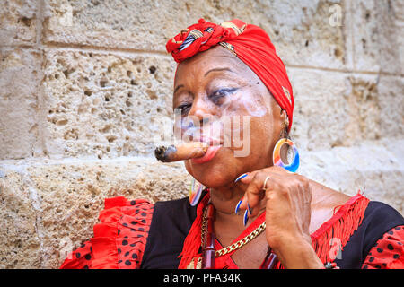 Femme fumant un cigare cubain coloré en tenue traditionnelle, portrait de femmes locales qui posent à La Havane, Cuba Banque D'Images