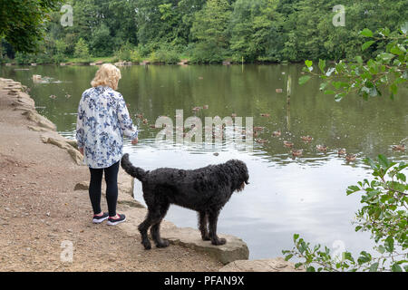 Blonde mature dame se trouve aux côtés du lac à trois soeurs la réserve naturelle locale, trois Sœurs Road, Ashton-In-Makerfield, Wigan avec son black Banque D'Images