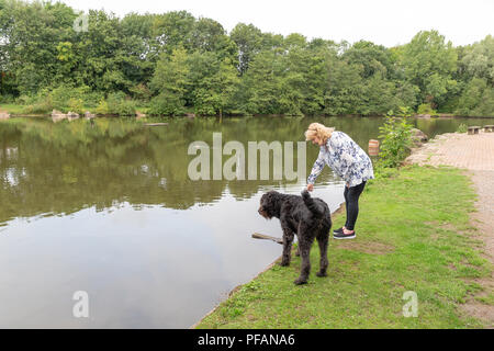 Blonde mature dame se trouve aux côtés du lac à trois soeurs la réserve naturelle locale, trois Sœurs Road, Ashton-In-Makerfield, Wigan avec son black Banque D'Images