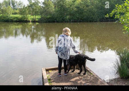 Blonde mature dame se trouve aux côtés du lac à trois soeurs la réserve naturelle locale, trois Sœurs Road, Ashton-In-Makerfield, Wigan avec son black Banque D'Images