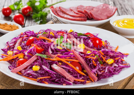 La viande, le maïs, salade de chou avec carottes tomates cerise et le persil sur plaque blanche sur une planche à découper avec de la moutarde en saucière et épices sur porcelaine Banque D'Images
