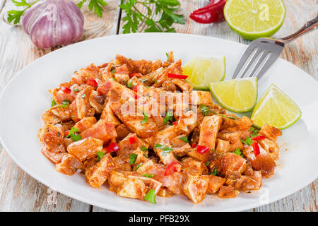 Aux oreilles de porc braisé ou Oreja de cerdo avec des épices, du piment, des morceaux de saupoudrer de persil citron vert sur blanc sur plateau en bois naturel anciennes cartes, clo Banque D'Images