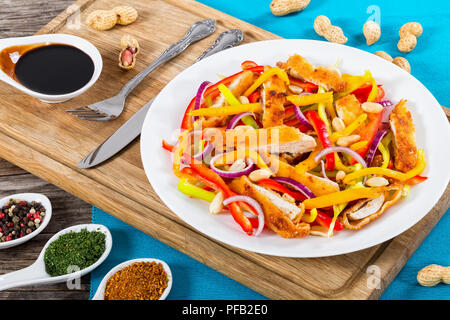 Crumbed pain de viande de poulet, mangue, les arachides, le poivron, l'oignon rouge sur blanc salade plat avec la moitié de la coupe en cubes de mangue, vinaigre de balsamique Banque D'Images