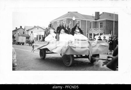 Photographie noir et blanc, montrant cinq filles, portant des robes et manteaux de fourrure, d'être tiré sur un char, avec des bâtiments, des spectateurs, des drapeaux américains et à l'arrière-plan, probablement photographié en Ohio dans la décennie suivant la Seconde Guerre mondiale, 1945. () Banque D'Images