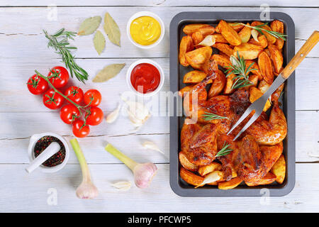 Poulet grillé croustillant d'or sur la plaque de cuisson avec les pommes de terre, l'ail. romarin. et fourchette à découper. Ingrédients sur fond blanc, vue d'en haut Banque D'Images