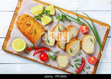 Close-up of pain de poisson haché maison remplie d'oignon, les œufs, les carottes, coupées en tranches et servi avec des oignons verts de printemps, persil, tranches de tomate, Banque D'Images