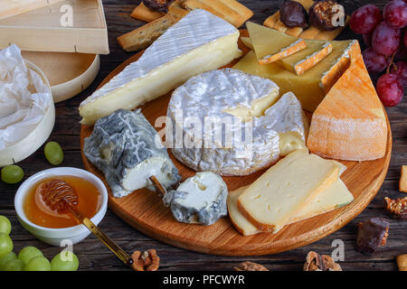 Plateau de fromages français servi avec des raisins et des noix sur fond de bois avec triangle et rond en bois des contenants faits de peuplier pour les emballages, voir fr Banque D'Images