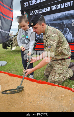 Soldat britannique démontrant la détection des mines à un enfant lors de la Journée des forces armées. Événement de relations publiques. 33 régiment du génie. Militaire Banque D'Images