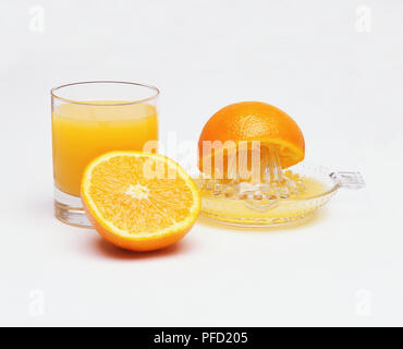 Les moitiés d'Orange, presse-agrumes et verre de jus d'orange fraîchement pressé. Banque D'Images