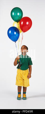 Boy holding quatre ballons remplis de gaz, jusqu'à Banque D'Images