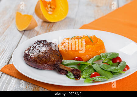 Cuisse de canard rôti au vin rouge avec le romarin, les épinards et la citrouille du porridge, close-up Banque D'Images