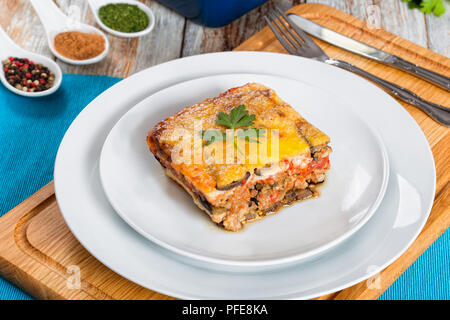 Partie de la moussaka en couches délicieux décoré de persil cuit pour recette authentique, sur des assiettes décorées de persil avec fourchette et couteau, sur whi Banque D'Images