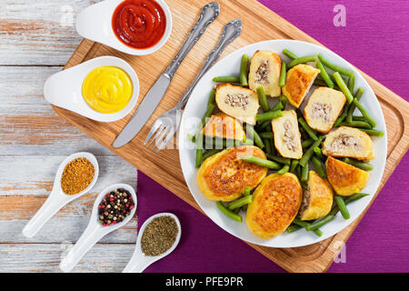 De délicieux plats italiens les galettes de pommes de terre à partir de la purée de pommes de terre remplis de viande de poulet avec des haricots vert sur blanc plateau, la moutarde et la sauce tomate sur b Banque D'Images