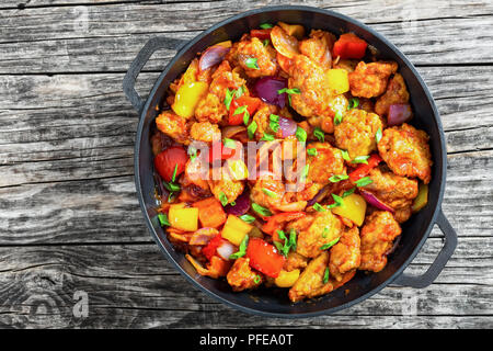 Croustillant aigre-doux de porc frit avec des légumes en morceaux poêle de fer sur fond de bois sombre ancien, chinois traditionnel, recette plat cuisine Cantonaise classique Banque D'Images