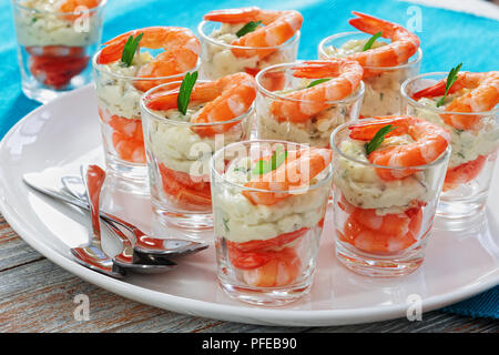 Crevettes cocktail individuels avec des tireurs de délicieux tartare sauce épicée décoré de feuilles de persil plat blanc sur le tapis de table pour Noël Banque D'Images