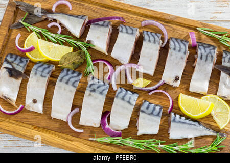 Filets marinés de maquereau poisson coupé en tranches sur la planche à découper avec le romarin, le citron, l'oignon rouge et d'épices, close-up, vue du dessus Banque D'Images