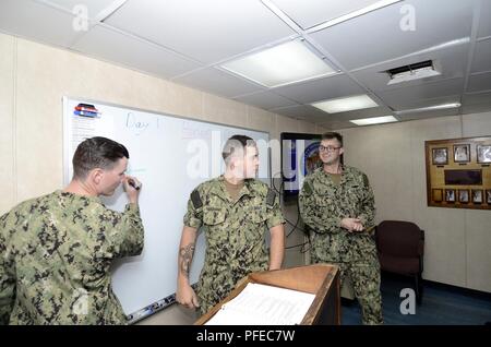 POINT POLARIS, Guam (30 mai 2018) - Technicien d'entretien des coques 1ère classe Patrick Shearer, droit, charge le chef de classe, spécialiste de la communication de masse Seaman Randall Ramaswamy, centre, pendant un cours de leadership de l'officier marinier Selectee à bord du sous-marin USS Frank offres câble (40). Frank, câble à Guam déployées à l'avant, les réparations, réarme et reprovisions U.S. Naval Forces déployées dans la région Indo-Pacifique. Banque D'Images