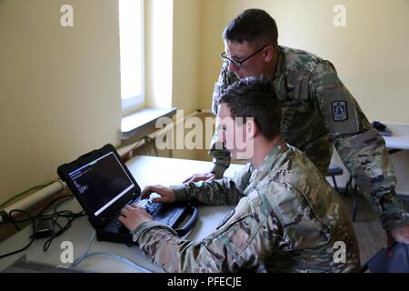 La CPS de l'armée américaine. Erik Lundquist (au clavier) et le Sgt. Michael Cole, tous deux attribués à la Compagnie Bravo, 86e, 11e Bataillon expéditionnaire Théâtre Signal Signal tactique Brigade, dépanner un commutateur à l'entreprise de l'avant lors de l'exercice NETOPS Grève Sabre, le 4 juin 2018 près de Powidz, Pologne. Grève de sabre de l'armée américaine est un exercice dirigé par l'Europe, impliquant environ 18 000 soldats de 19 nations participantes ayant lieu en Lituanie, l'Estonie, la Lettonie et la Pologne à partir de juin 3-15, 2018. Banque D'Images